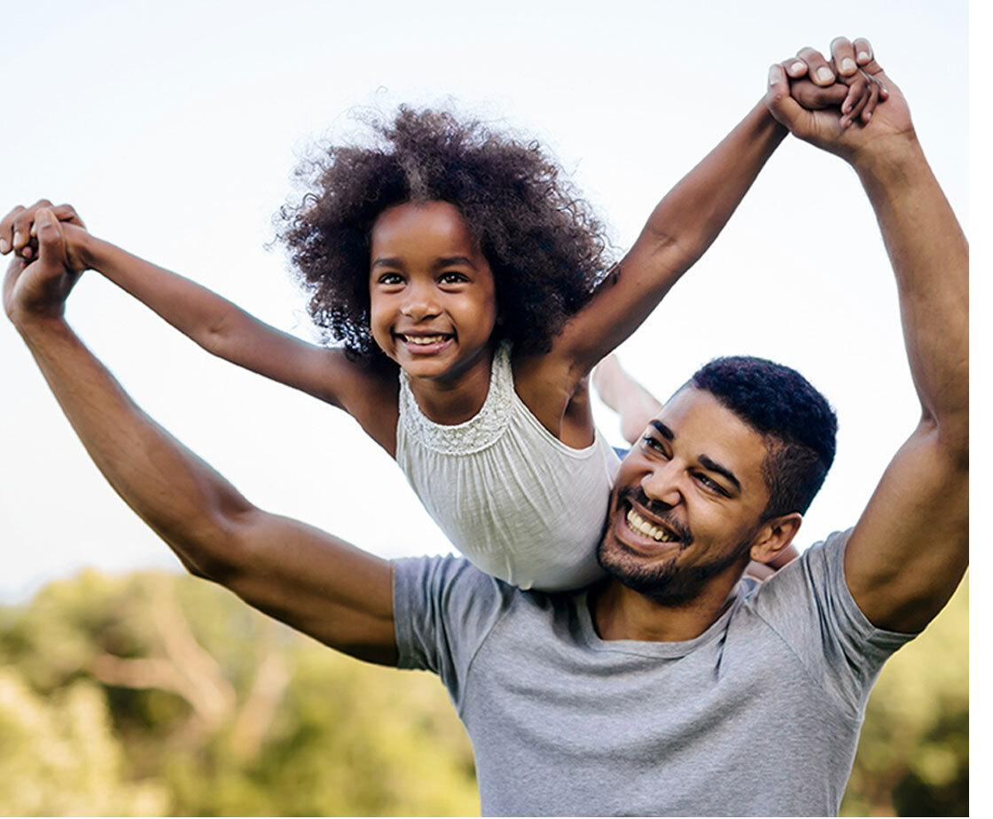 A father lifting his smiling daughter outdoors